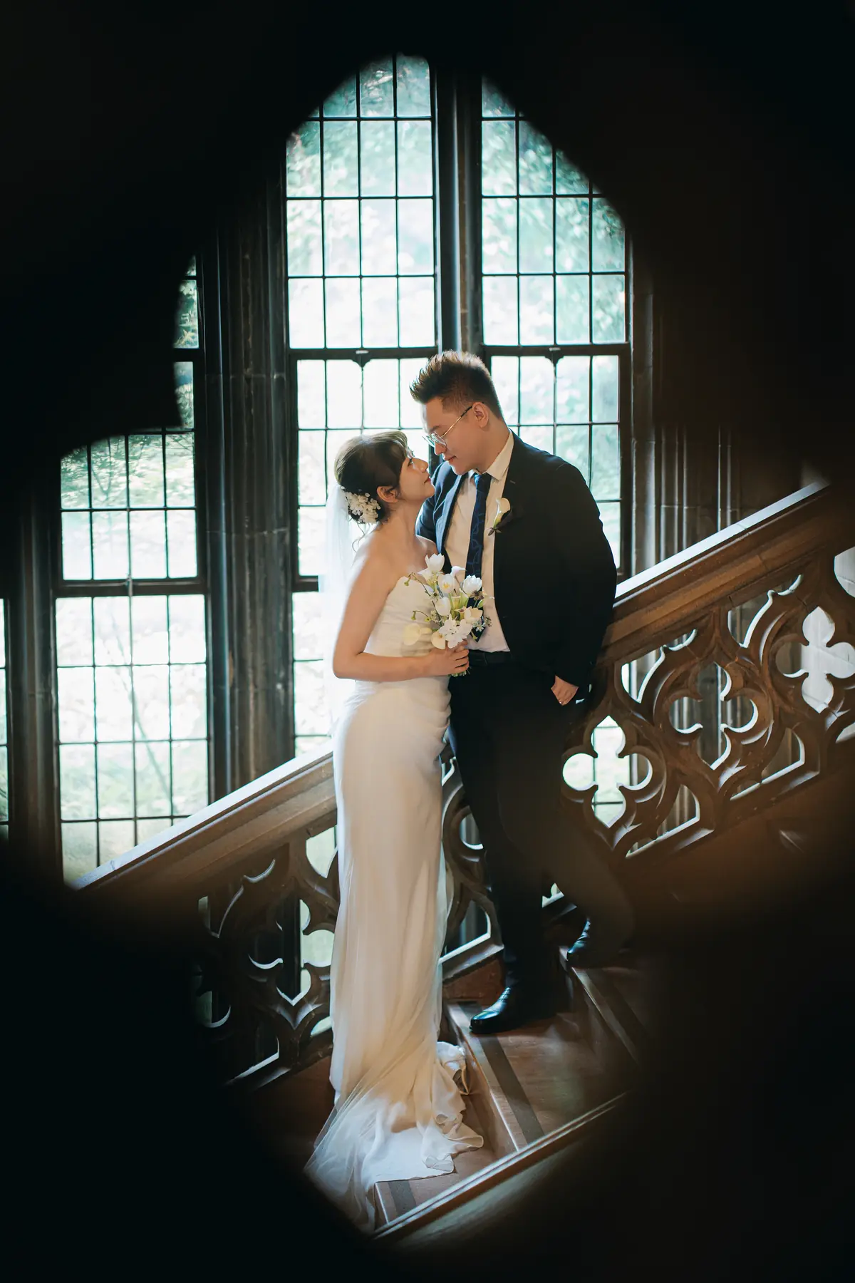 Newlyweds by a dramatic arched window