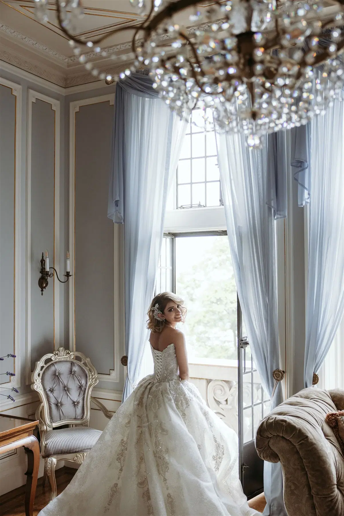 Bride in an ornate interior beneath a chandelier