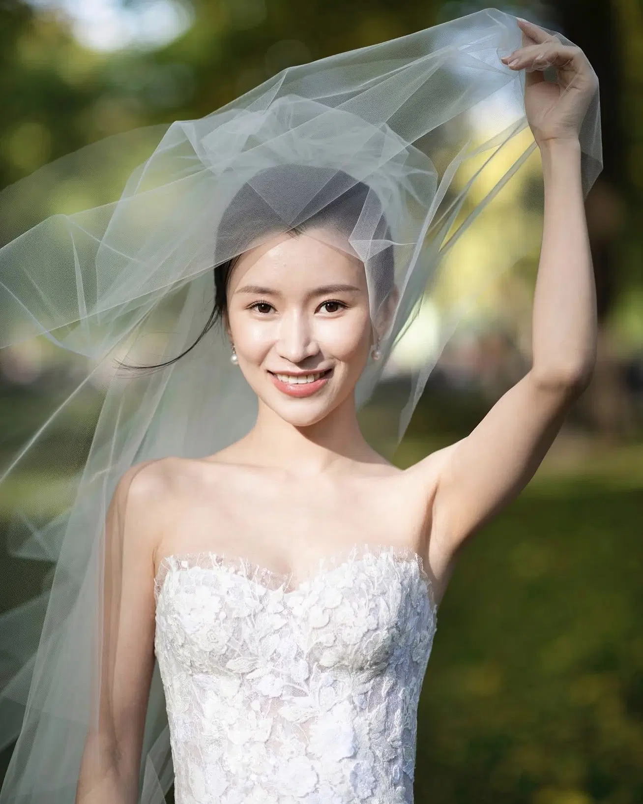 Bride lifting a veil outdoors