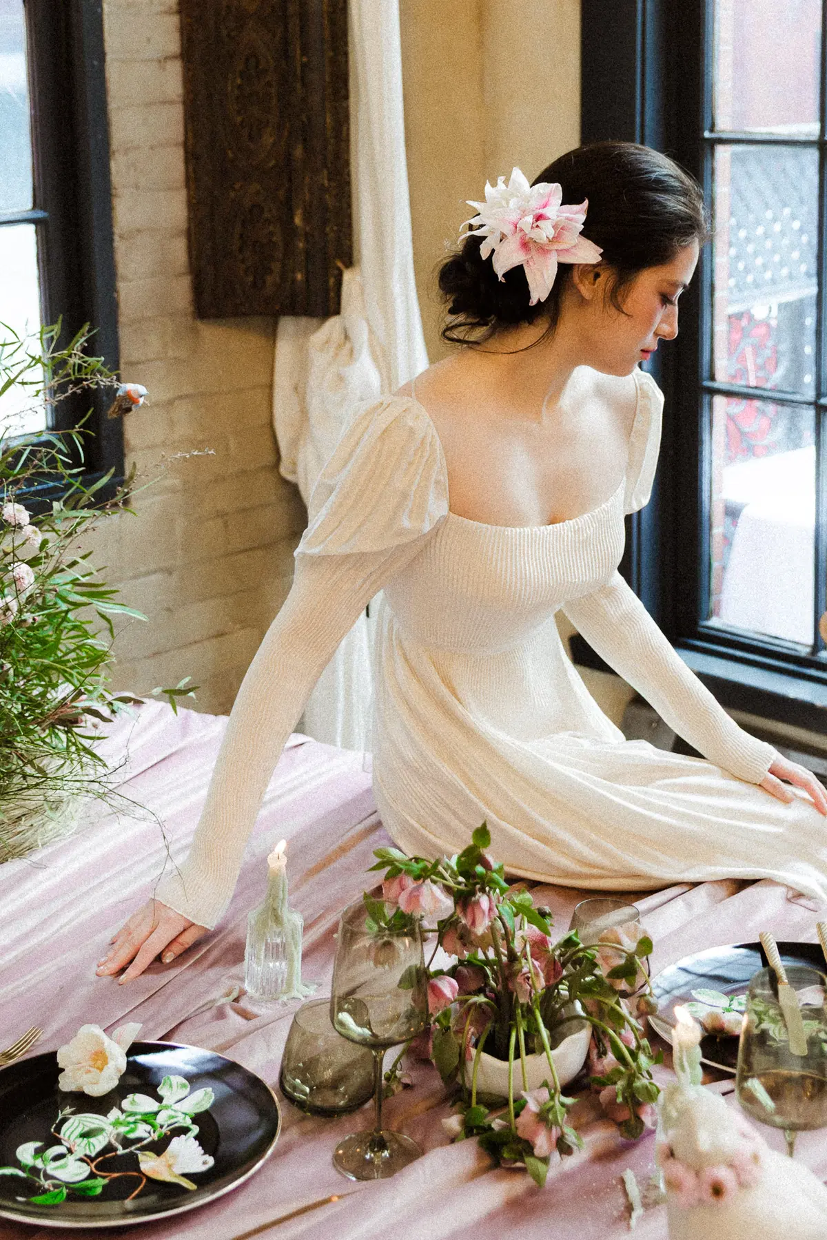 Bride arranging florals beside a window